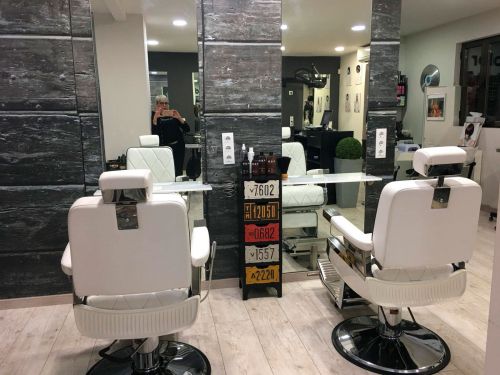 Detalle de dos sillones de peluquería blancos frente a espejos hasta el suelo